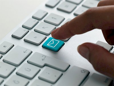 Hand drückt eMail-Taste auf Tastatur: Datenmeldung, Reporting und Berichtswesen durch Pensus Pensionsmanagement