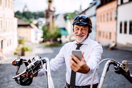 Rentner schaut lächelnd auf sein Handy und hat den Durchblick bei seiner Rentenabrechnung von Pensus